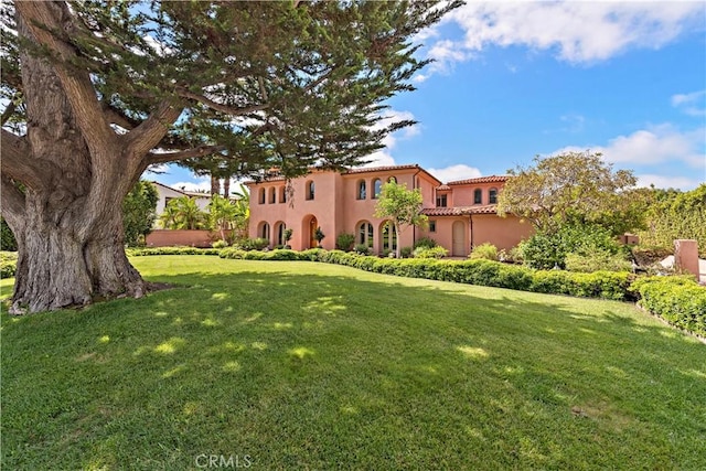 view of front facade with a tile roof, a front lawn, and stucco siding