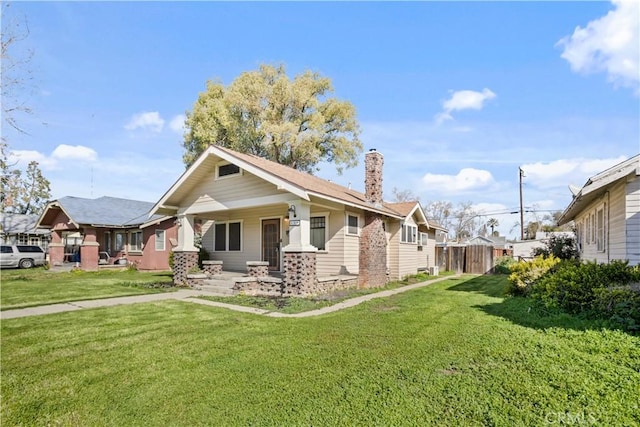 view of home's exterior featuring a yard, a porch, a chimney, and fence