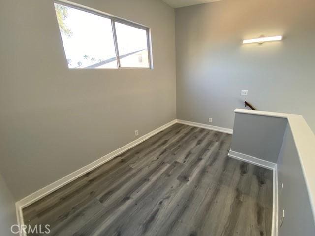 empty room with dark wood-style floors and baseboards