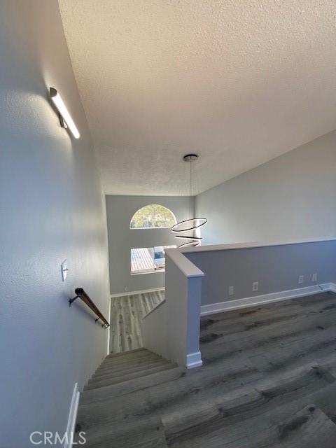 stairway with a textured ceiling, baseboards, and wood finished floors