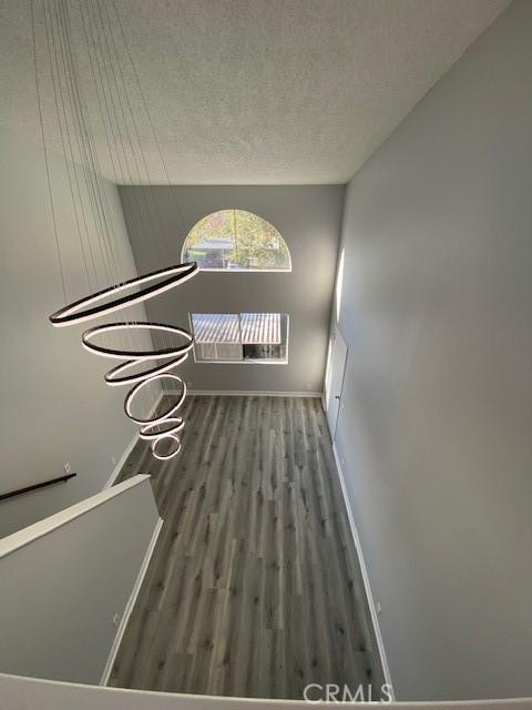 spare room featuring baseboards, a textured ceiling, and wood finished floors