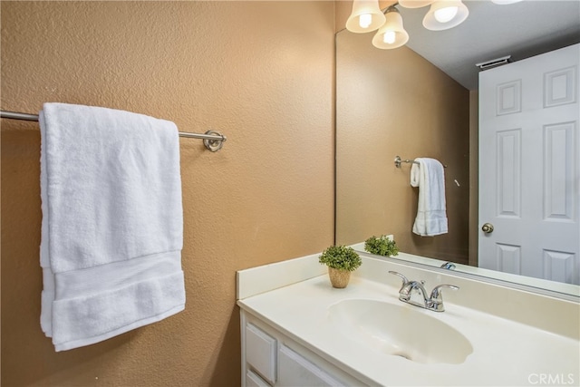 bathroom with a textured wall and vanity