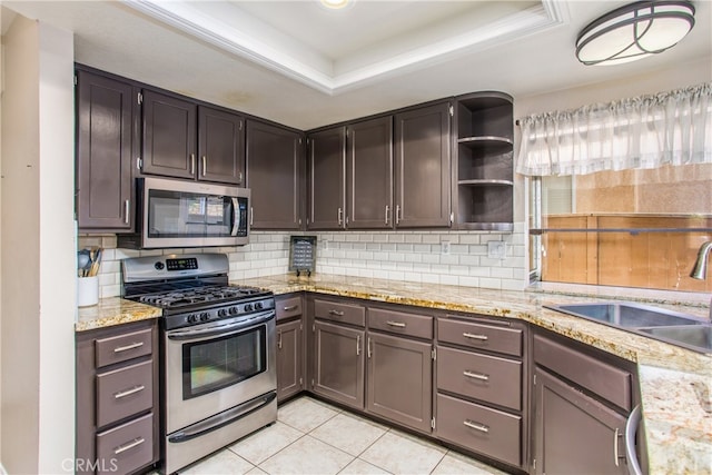 kitchen with a tray ceiling, open shelves, stainless steel appliances, backsplash, and a sink