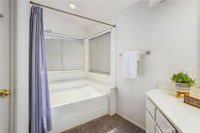 full bathroom with lofted ceiling, vanity, a bath, and baseboards