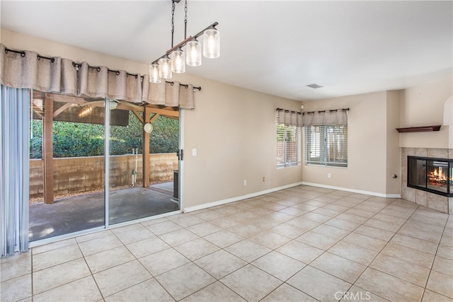 interior space with light tile patterned flooring, a tile fireplace, visible vents, and baseboards