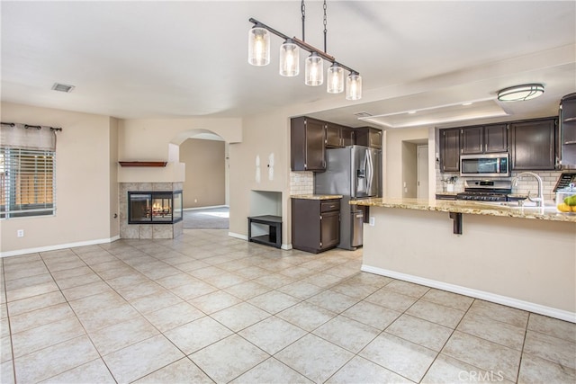 kitchen featuring open floor plan, dark brown cabinets, appliances with stainless steel finishes, and a breakfast bar