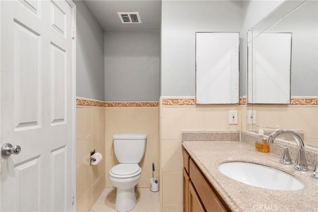 half bath with toilet, tile walls, vanity, visible vents, and tile patterned floors