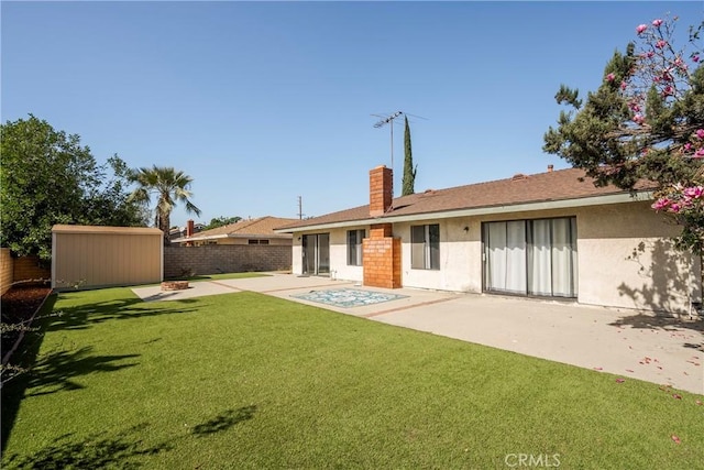 rear view of house with an outbuilding, a fenced backyard, stucco siding, a shed, and a patio area