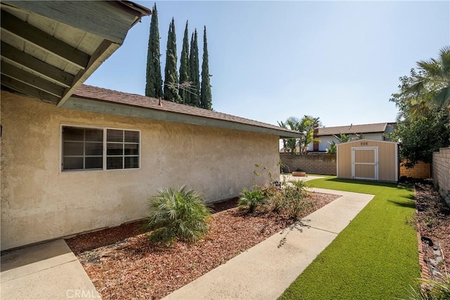 view of home's exterior featuring an outbuilding, stucco siding, a lawn, a storage shed, and a fenced backyard