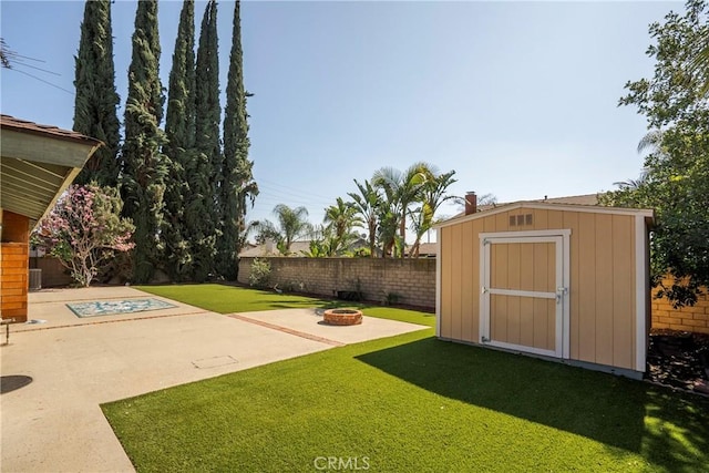 view of yard with a storage shed, an outdoor fire pit, a fenced backyard, an outdoor structure, and a patio area