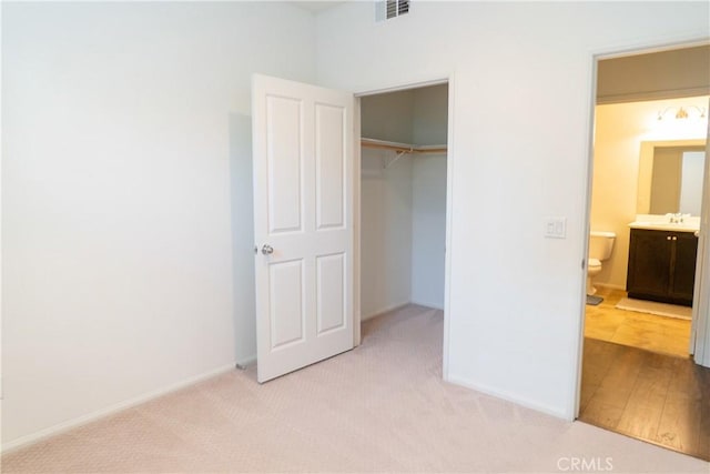 unfurnished bedroom with baseboards, visible vents, a sink, carpet floors, and a closet