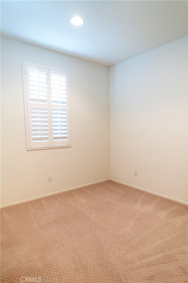 empty room featuring recessed lighting, light carpet, and baseboards