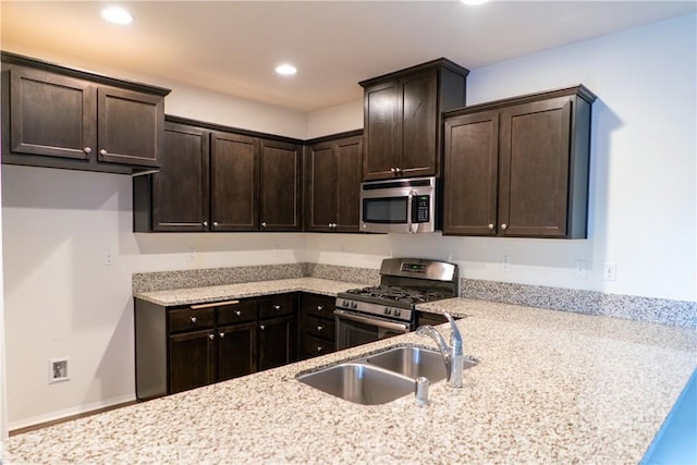 kitchen with light stone counters, recessed lighting, a sink, dark brown cabinets, and appliances with stainless steel finishes