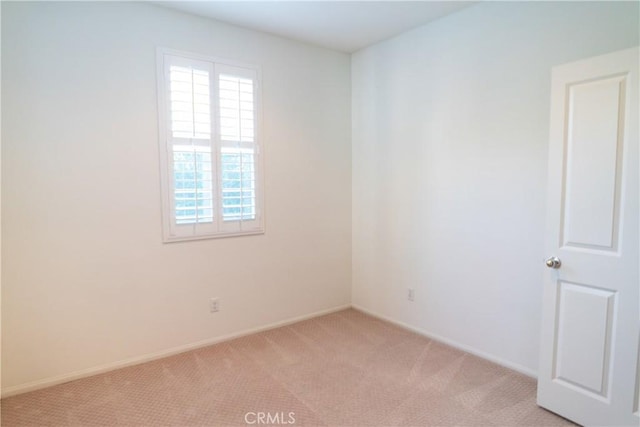 unfurnished room with light carpet and baseboards