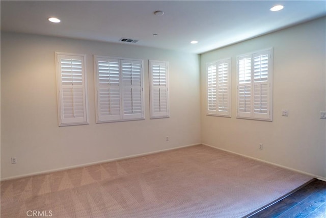 carpeted spare room featuring visible vents, baseboards, and recessed lighting