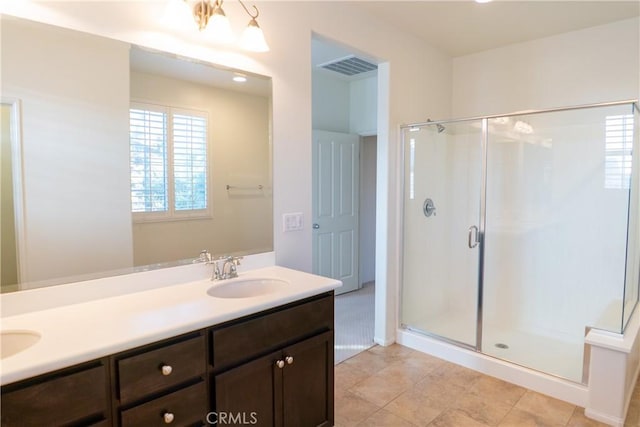 bathroom featuring double vanity, a stall shower, a sink, and visible vents