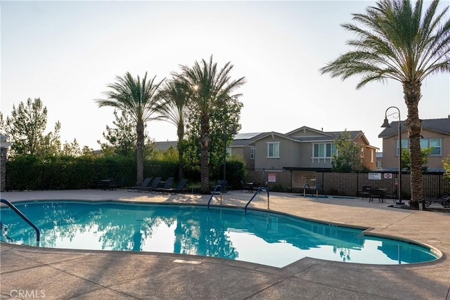 pool with a patio, fence, and a residential view