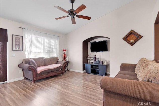 living area with lofted ceiling, baseboards, ceiling fan, and light wood finished floors