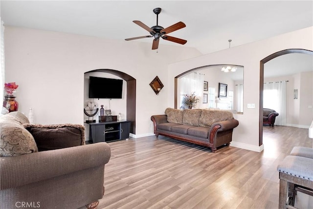 living room with arched walkways, light wood-type flooring, lofted ceiling, and baseboards