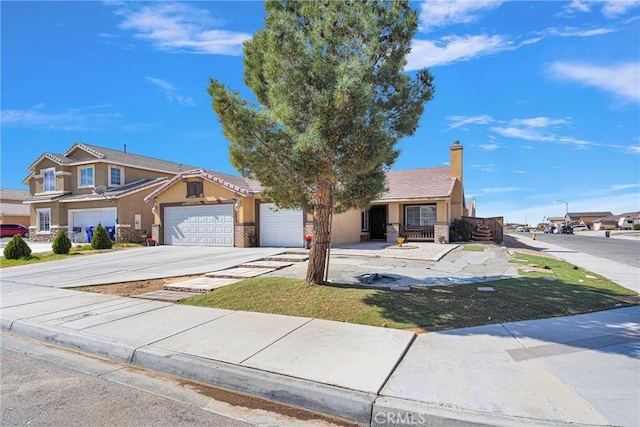 view of front facade with concrete driveway, a chimney, an attached garage, and stucco siding