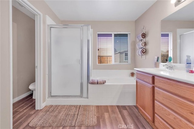 bathroom featuring toilet, wood finished floors, vanity, a shower stall, and a bath