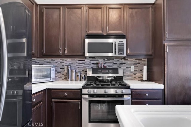 kitchen featuring stainless steel appliances, tile counters, and tasteful backsplash