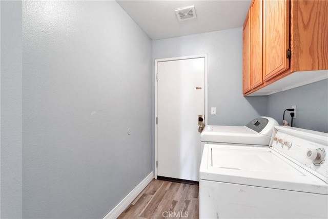 laundry room featuring separate washer and dryer, visible vents, baseboards, light wood-type flooring, and cabinet space