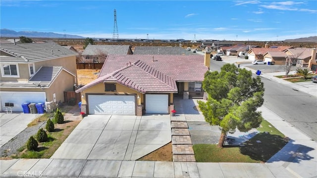 view of front facade featuring a residential view, concrete driveway, a tiled roof, and an attached garage