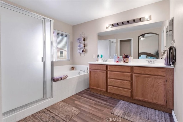 full bath with a garden tub, wood finished floors, a sink, a shower stall, and double vanity