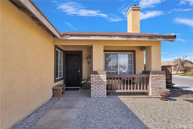 entrance to property with a porch and stucco siding