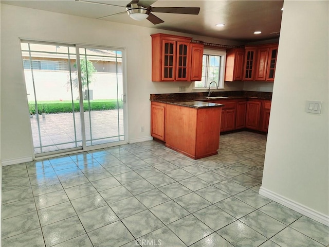 kitchen featuring glass insert cabinets, dark countertops, and baseboards