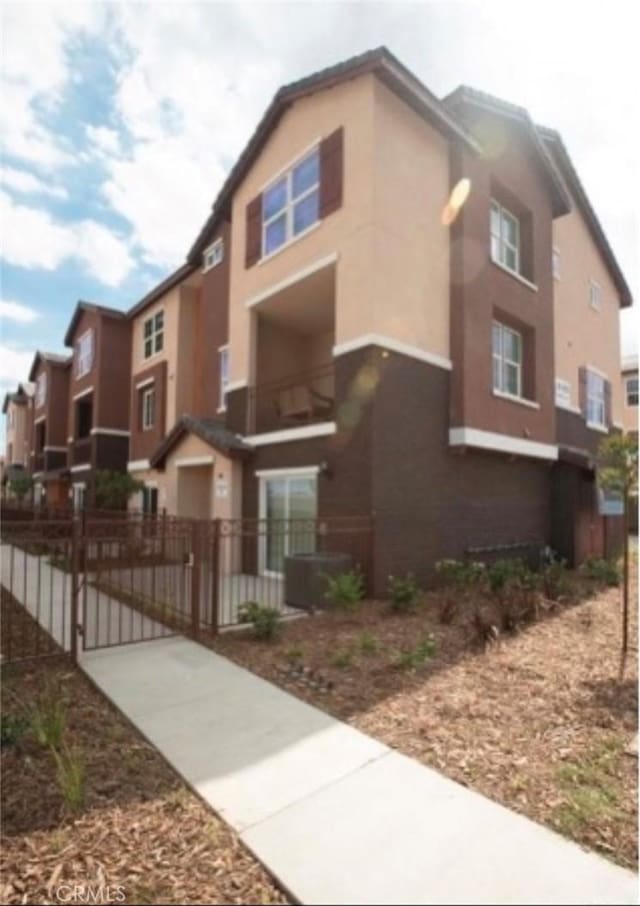 exterior space featuring stucco siding, fence, and a gate