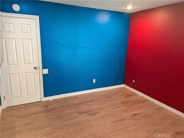 spare room with baseboards and wood finished floors