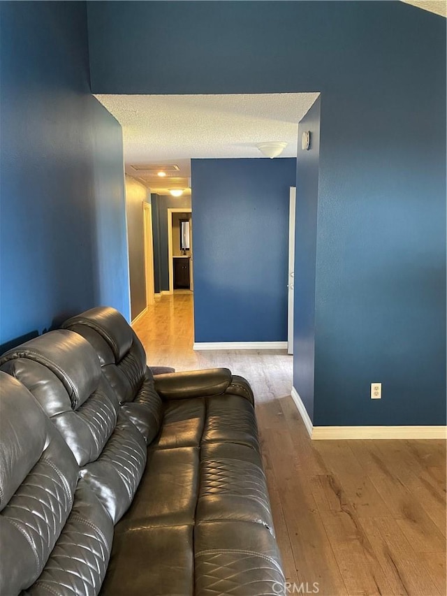 living area featuring a textured ceiling, baseboards, and wood finished floors