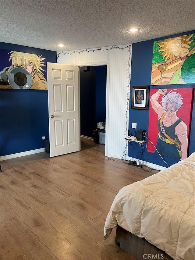 bedroom featuring a textured ceiling, baseboards, and wood finished floors