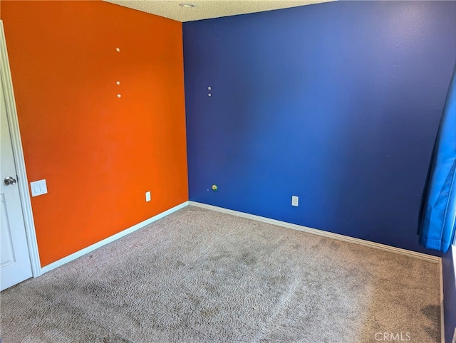 carpeted spare room with a textured ceiling and baseboards