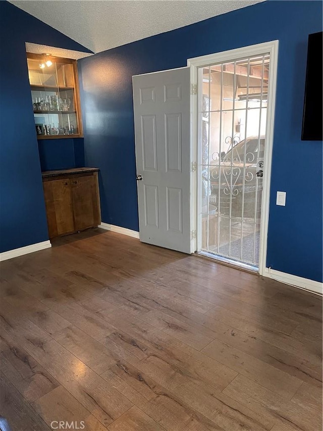 unfurnished room with vaulted ceiling, baseboards, and wood finished floors