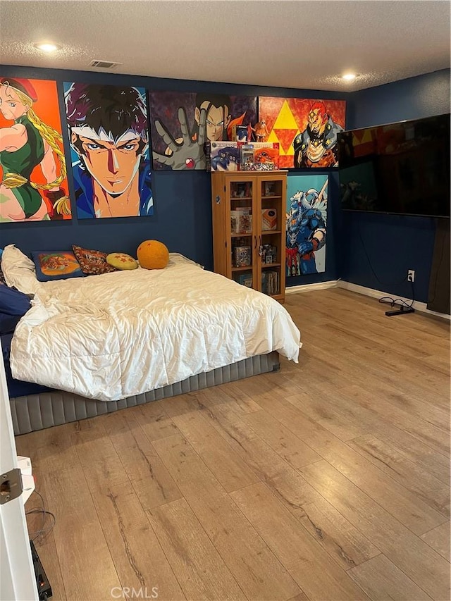 bedroom featuring visible vents, a textured ceiling, and wood finished floors