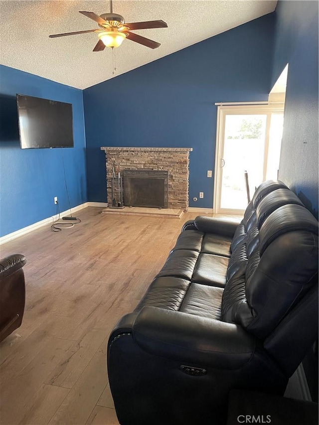 living room with lofted ceiling, a textured ceiling, a fireplace, and wood finished floors