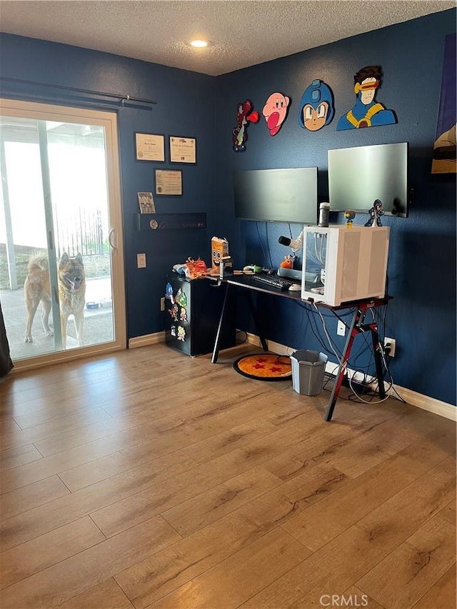 home office with light wood finished floors, baseboards, and a textured ceiling