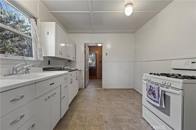 1779 Virginia St, Wrightwood, CA 92397 - kitchen with light tile patterned floors, white range with gas stovetop, a sink, white cabinets, and light countertops