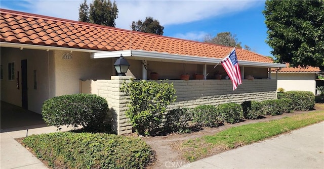 view of side of home with a tile roof and stucco siding