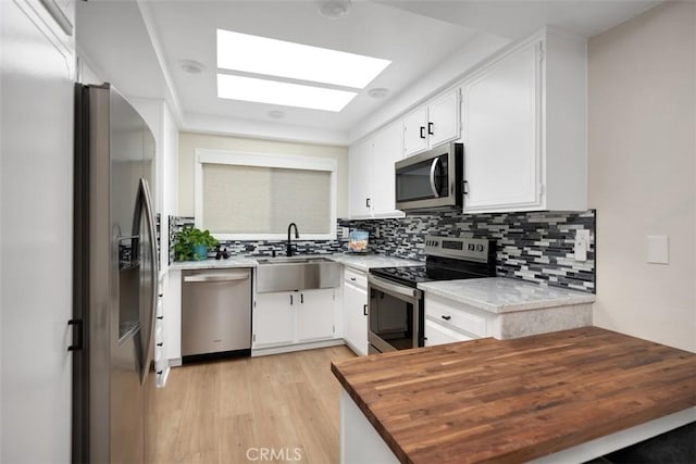 3311 Via Carrizo Unit P, Laguna Woods, CA 92637 - kitchen with stainless steel appliances, light wood-style floors, decorative backsplash, and white cabinets