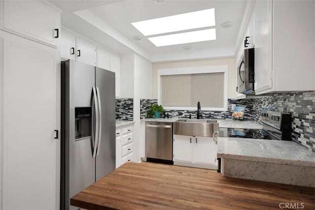3311 Via Carrizo Unit P, Laguna Woods, CA 92637 - kitchen featuring stainless steel appliances, tasteful backsplash, white cabinetry, light stone countertops, and light wood-style floors