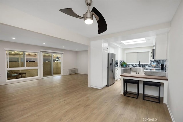 3311 Via Carrizo Unit P, Laguna Woods, CA 92637 - kitchen with stainless steel appliances, white cabinetry, decorative backsplash, light wood-type flooring, and a ceiling fan