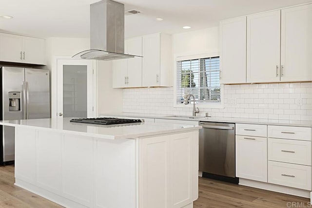 kitchen with a sink, a kitchen island, white cabinets, appliances with stainless steel finishes, and island exhaust hood