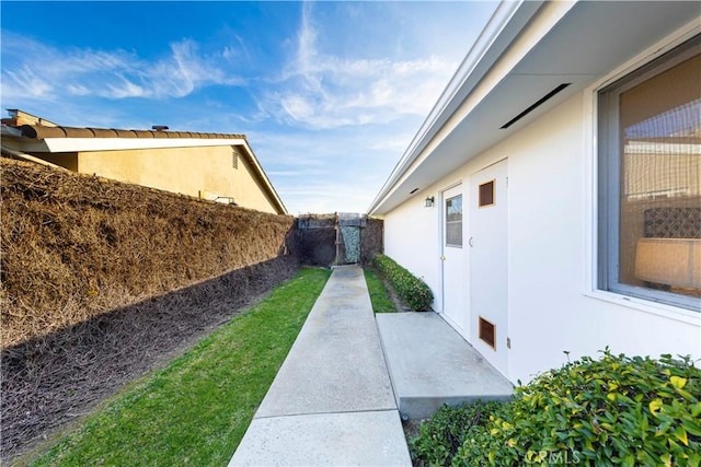 view of side of home featuring a fenced backyard and stucco siding