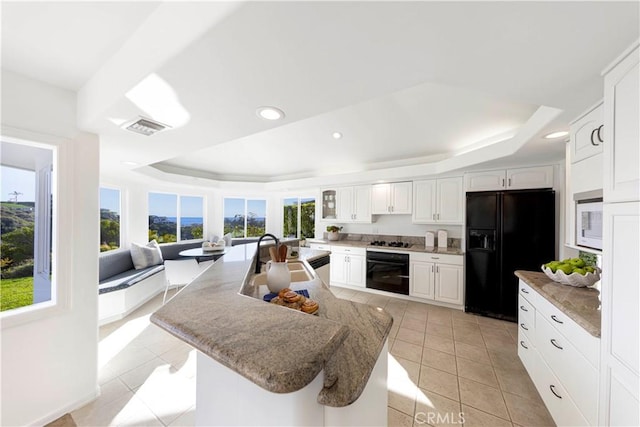 kitchen with white cabinets, a raised ceiling, a kitchen island, black appliances, and a sink