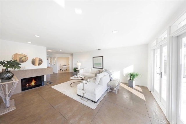 living area with concrete flooring, a lit fireplace, french doors, and recessed lighting