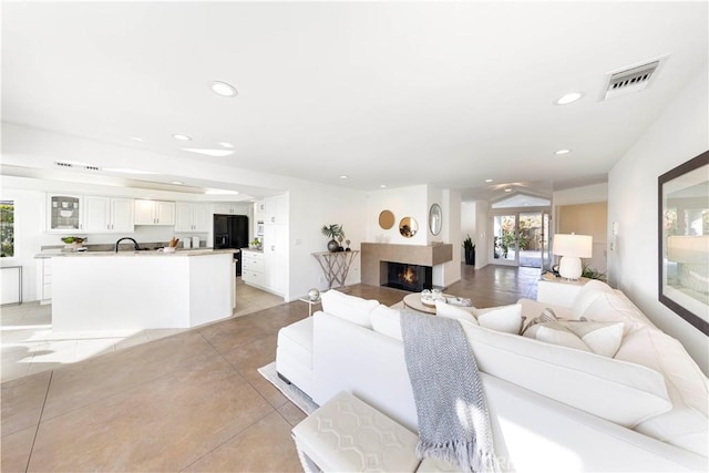 living room with a warm lit fireplace, visible vents, and recessed lighting